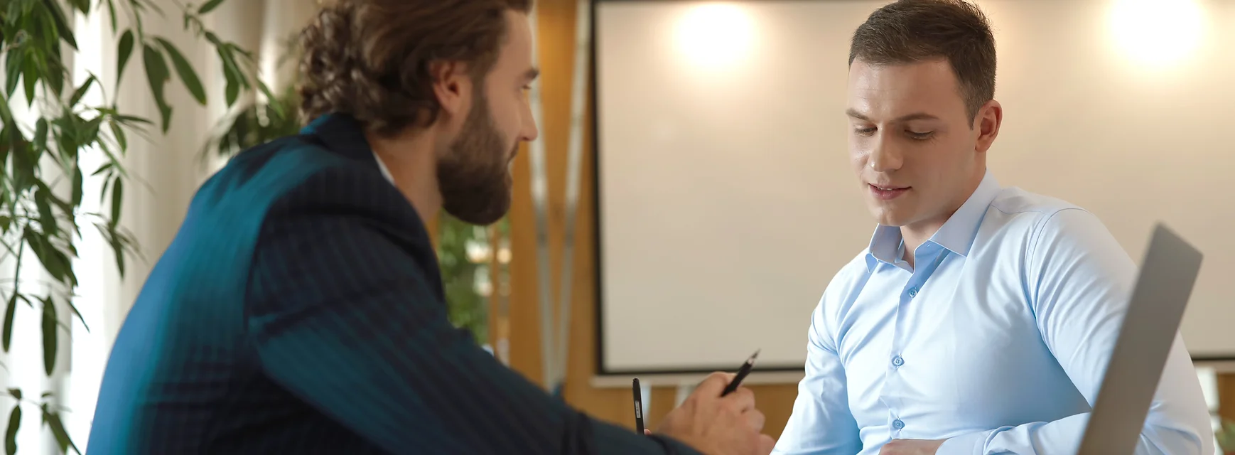 Two professionals having a meeting in an office with a whiteboard