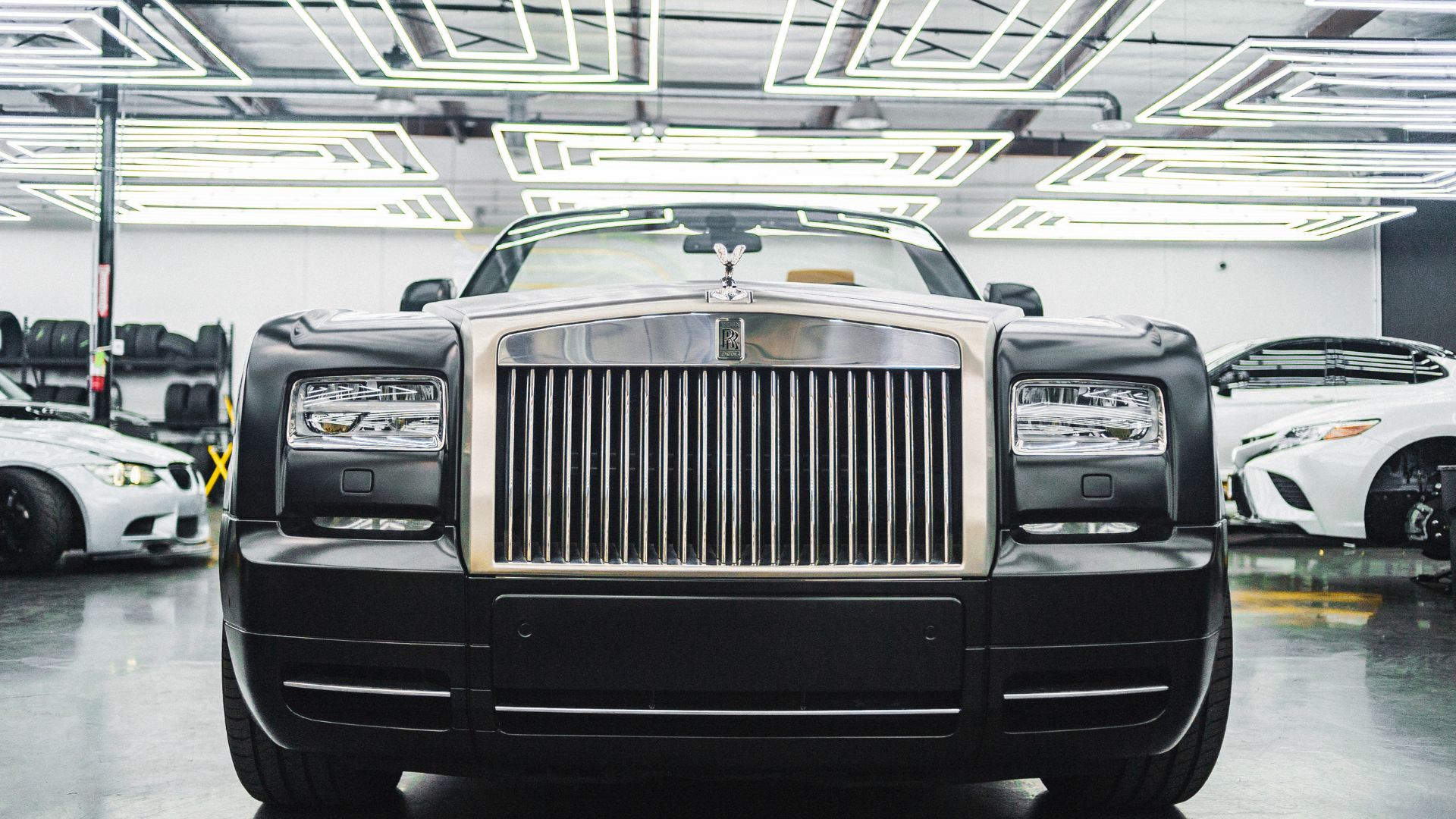 Luxury Rolls-Royce sedan with iconic grille in modern showroom setting