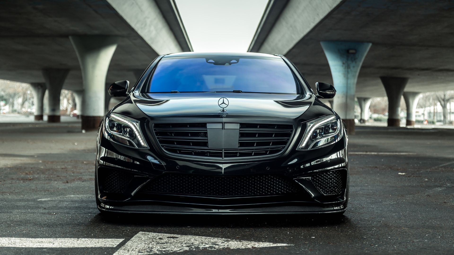 Black Mercedes-Benz sedan parked under concrete bridge architectural structure