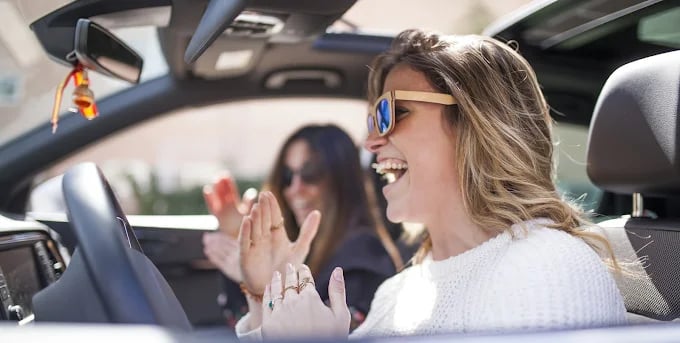Two women laughing and having fun while driving together in a car